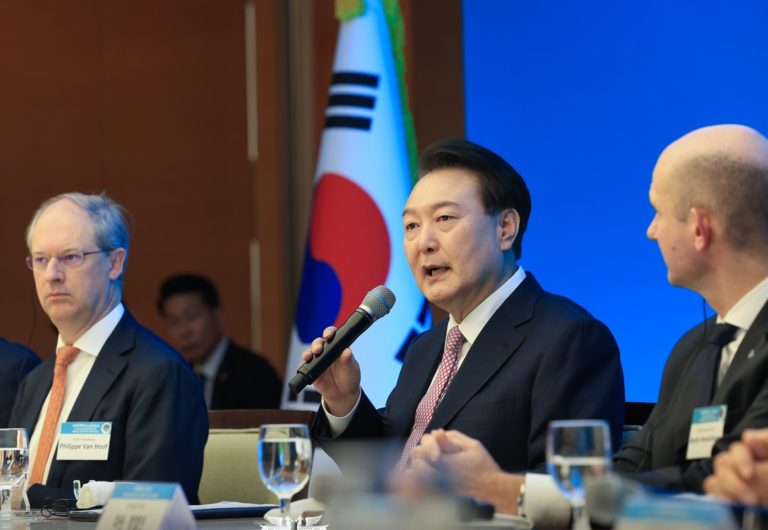 Le président coréen Yoon Suk Yeol tient un micro dans sa main et s'exprime autour d'une table ronde