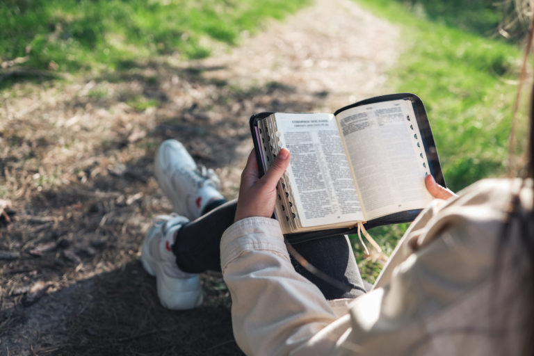Une jeune femme lit la Bible dans la nature