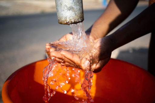 Un jet d'eau coule sur les mains d'une personne africaine