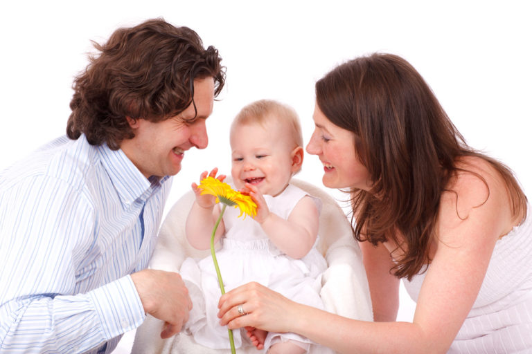 un père et une mère amuse leur bébé avec une fleur