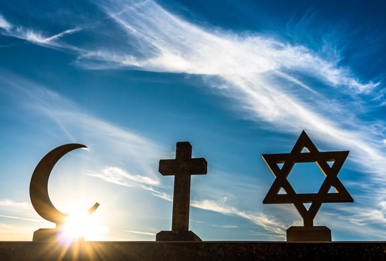 Les symbole religieux suivants, la lune de l'islam, la croix chrétienne et l'étoile Juive sont représentés devant un levé de soleil
