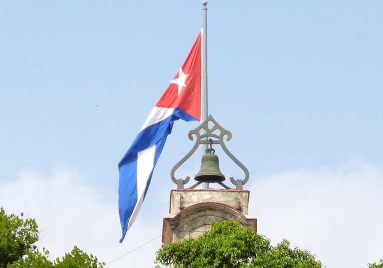 Un drapeau accroché sur un poteau en haut d'une église avec une cloche