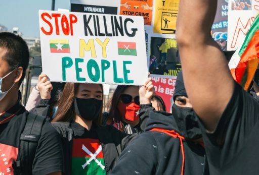 Des hommes et des femmes manifestent avec des pancartes "Arrêtez de tuer mon peuple"