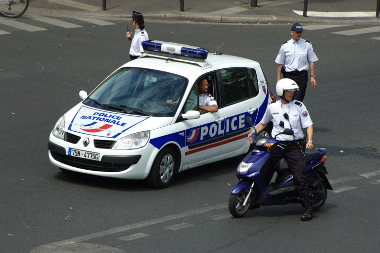 Un policier en voiture et trois policiers en moto montent la garde dans la rue