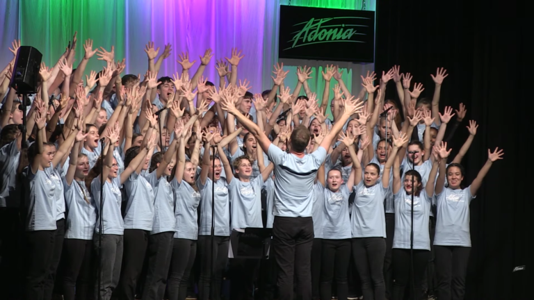 Des dizaines de jeunes chantent sur scène durant un spectacle Adonia