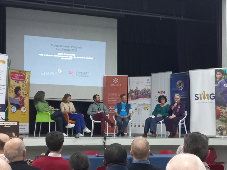 Six personnes, assises sur des chaises sur une scène durant le Forum mission intégrale. C'est un temps de discussion. Une dame parle dans un micro en regardant vers les auditeurs.