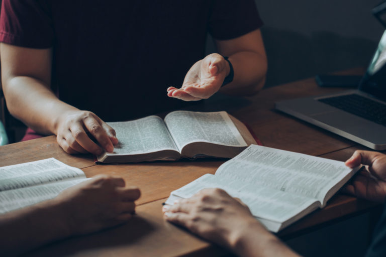 Les groupes d'amis chrétiens lisent et étudient la Bible ensemble dans une maison éclairée par une fenêtre.