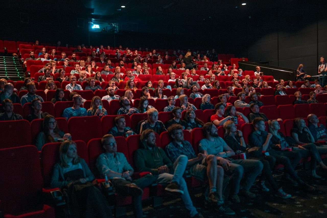 Une salle de cinéma avec des spectateurs assis dans des fauteuils rouges