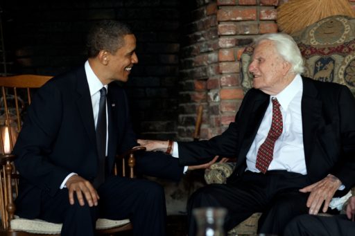 Barack Obama et Billy Graham en train de discuter dans des fauteuils.