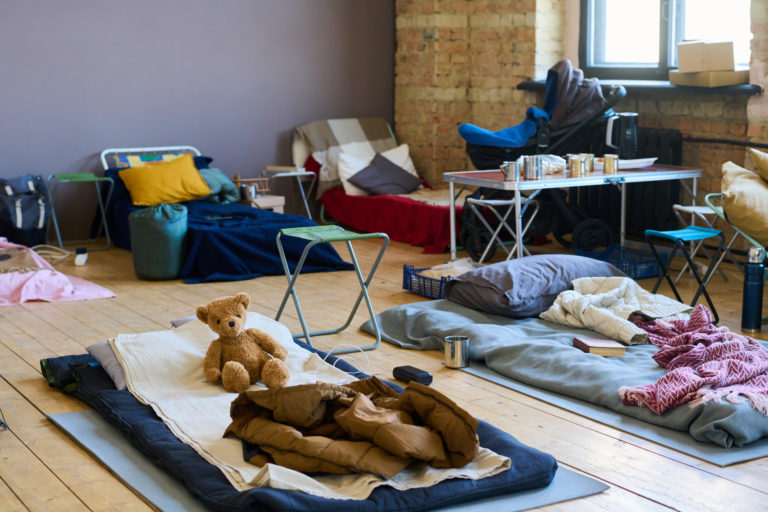 Des couchages de fortune sont installés dans un local. La pièce est vide.