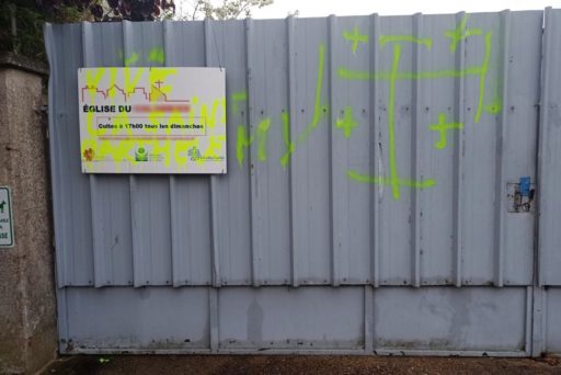 Un tag, inscrit en jaune fluo, sur le portail d'une église évangélique baptiste avec l'inscription «Vive la Saint-Barthélemy»