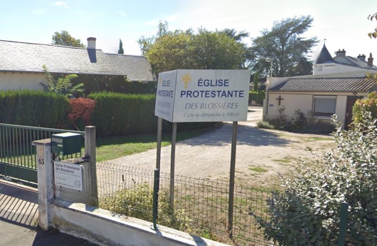 Vue de la rue de l'église évangélique des Blossières à Orléans, un panneau présente ce lieu comme une église protestante et une croix est apposée sur la façade de l'édifice au second plan