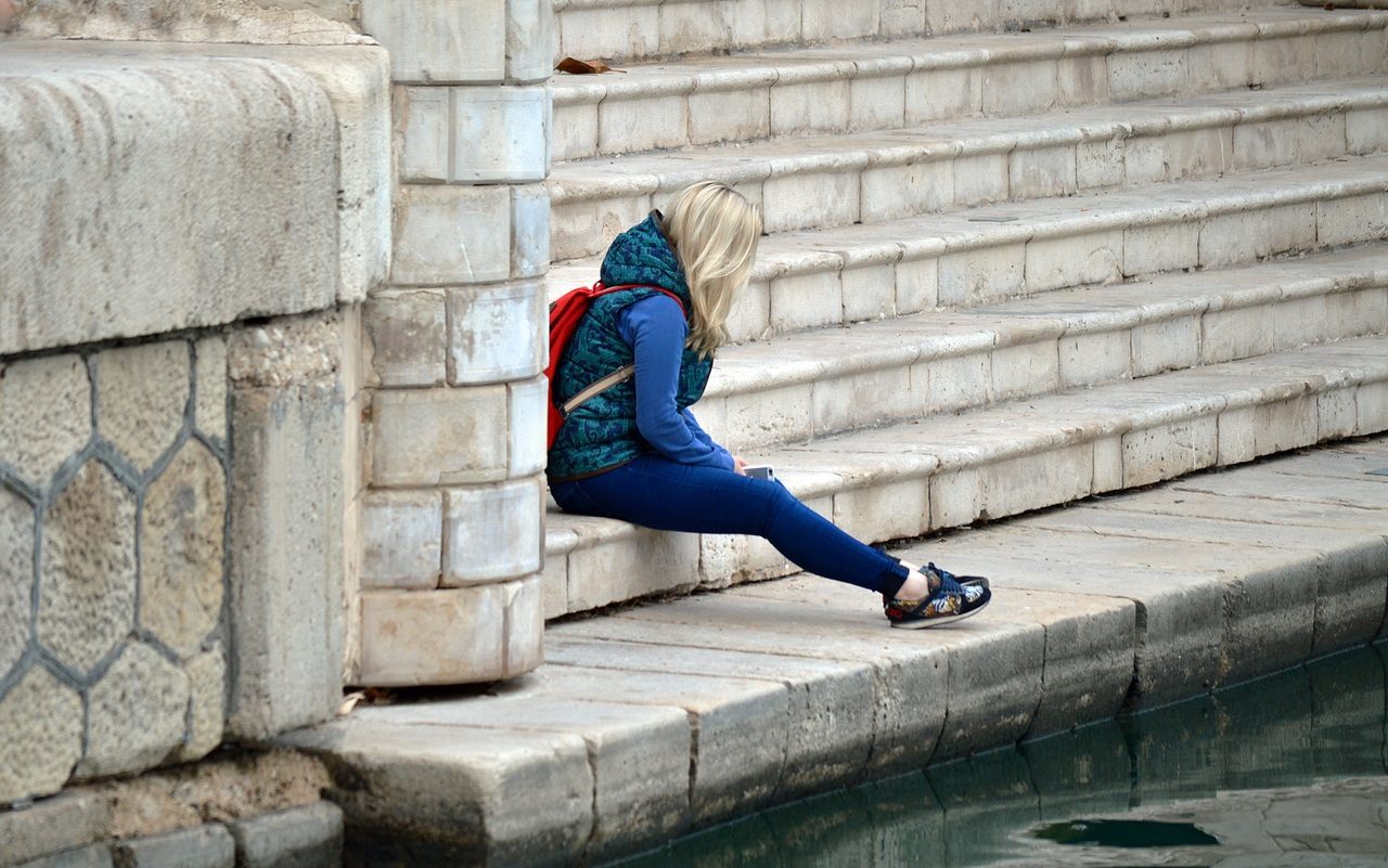 Une jeune fille est assise sur des marches, en extérieur