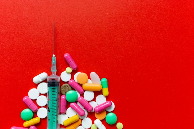 Une seringue est posée près d'une poignée de médiacaments