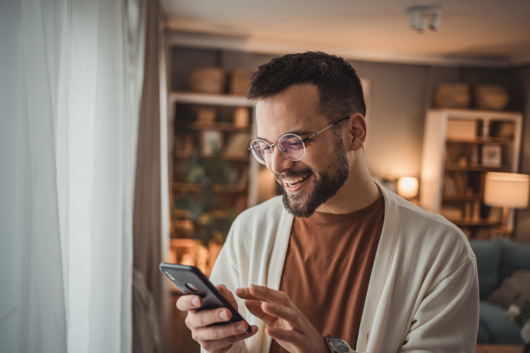 Un homme jeune sourit en consultant son smartphone