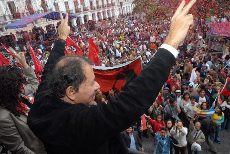 Daniel Ortega, du haut d'une estrade, salue la foule qui brandit des drapeaux du Nicaragua