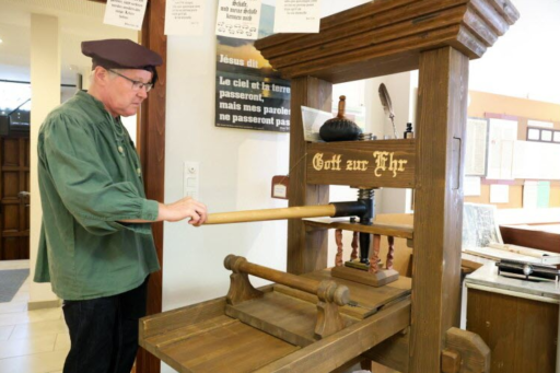 Un homme actionne une presse Gutenberg