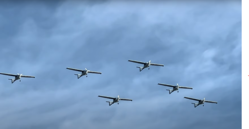 Six avions électriques volent en formation. Le ciel est nuageux.