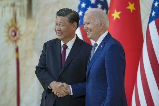 Xi Jinping et Joe Biden se serrent la main face aux photographes avec en arrière plan les drapeaux des Etats-Unis et de la Chine