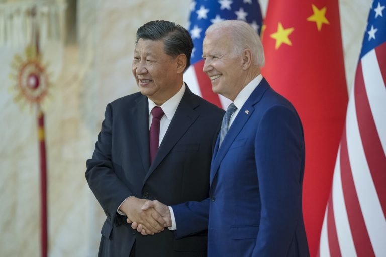 Xi Jinping et Joe Biden se serrent la main face aux photographes avec en arrière plan les drapeaux des Etats-Unis et de la Chine