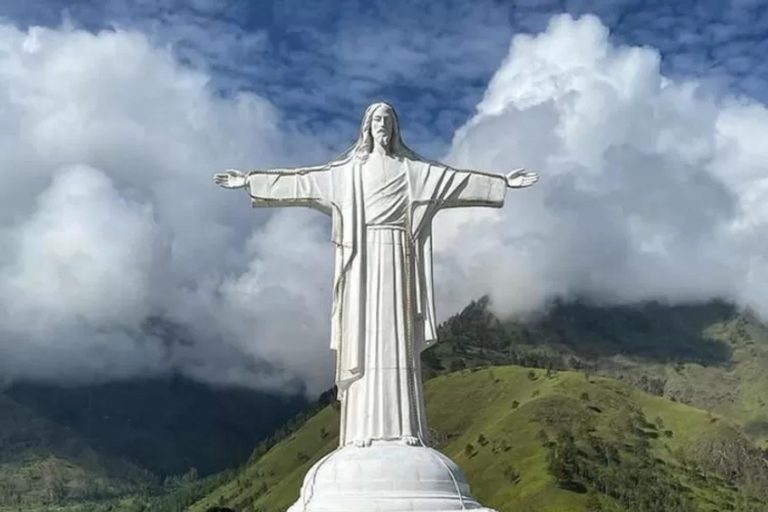 La statue représentant Jésus tout de blanc entouré des nuages dans le ciel