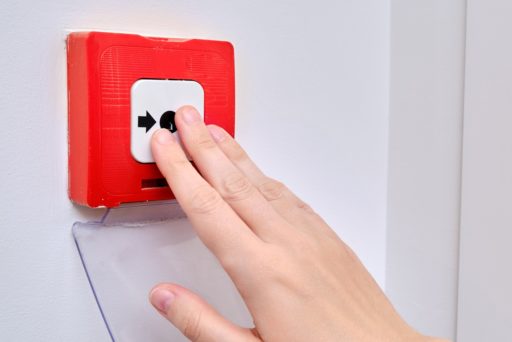 Une main s'apprête à appuyer sur un bouton d'alarme