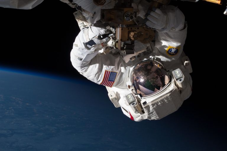 Photo d'un cosmonaute en apesanteur dans l'espace. Il a la tête vers le bas.