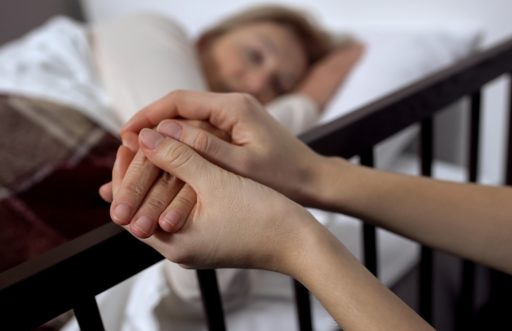 Une femme allongée sur un lit, des mains lui caressent sa main