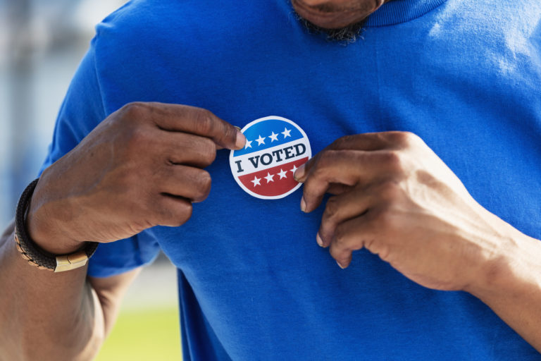 Un homme colle un autocollant "I voted" sur son tee-shirt