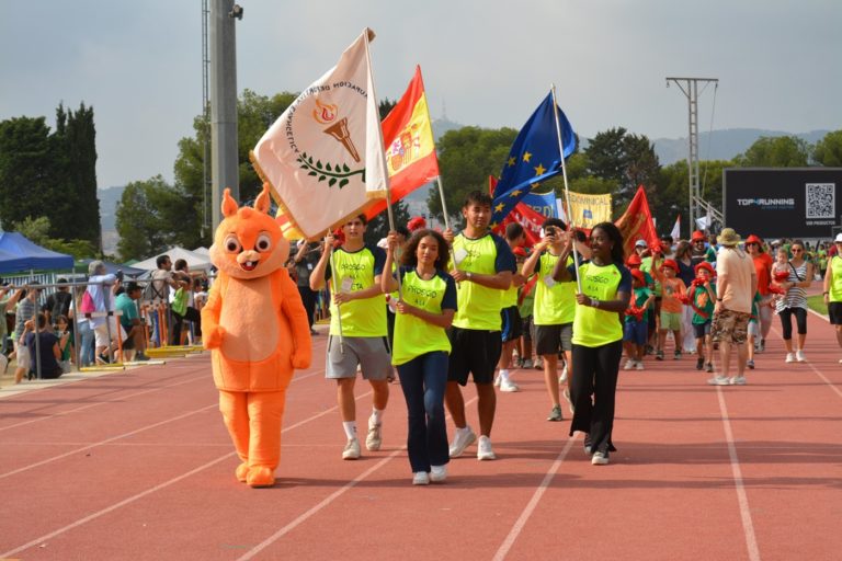 Des jeunes et une mascotte portent des drapeaux