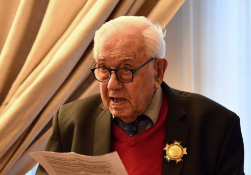 Samuel Sahagian avec la médaille de l'Ordre de l'Amitié sur sa veste est en train de lire un discours, il tient une feuille dans sa main