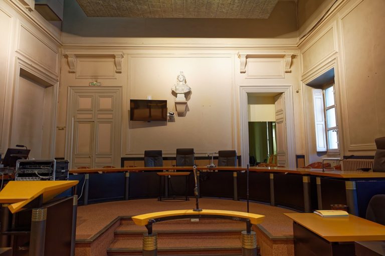 Cour d'assise : vue de la barre des témoins. Sous un buste de Marianne, la place du président et des jurés