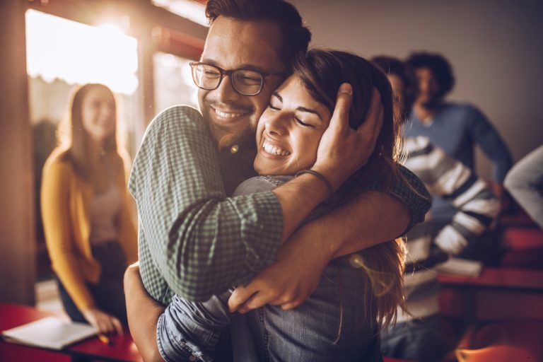 Un homme et une femme souriants ont le visage collé et s'enlace amoureusement