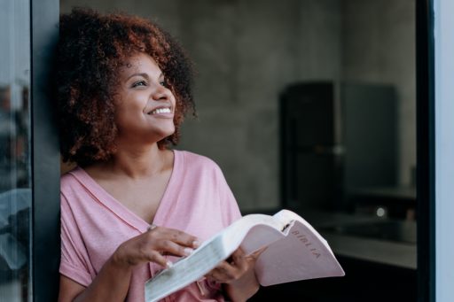 Une femme souriante tient dans ses mains une Bible en portugais