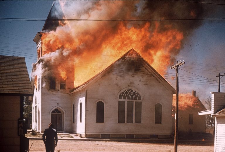 La toiture d'une eglise brûle, un panache de fumée noire se dégage au dessus des flammes