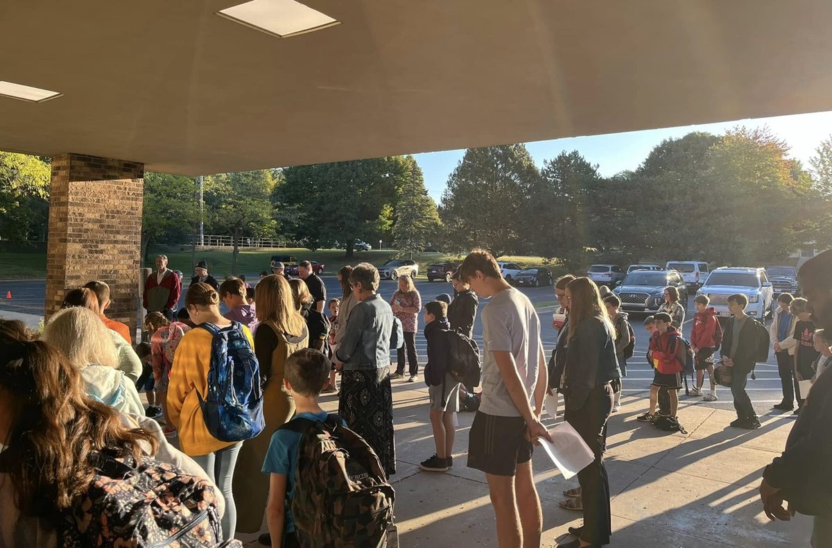 Des enfants et des adultes prient debout dans la cour de l'école chrétienne Abundant Life