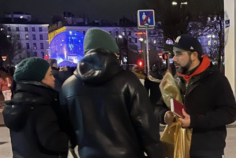 Un jeune chrétien discute avec un couple et s'apprête à leur donner une bible qu'il tient dans la main