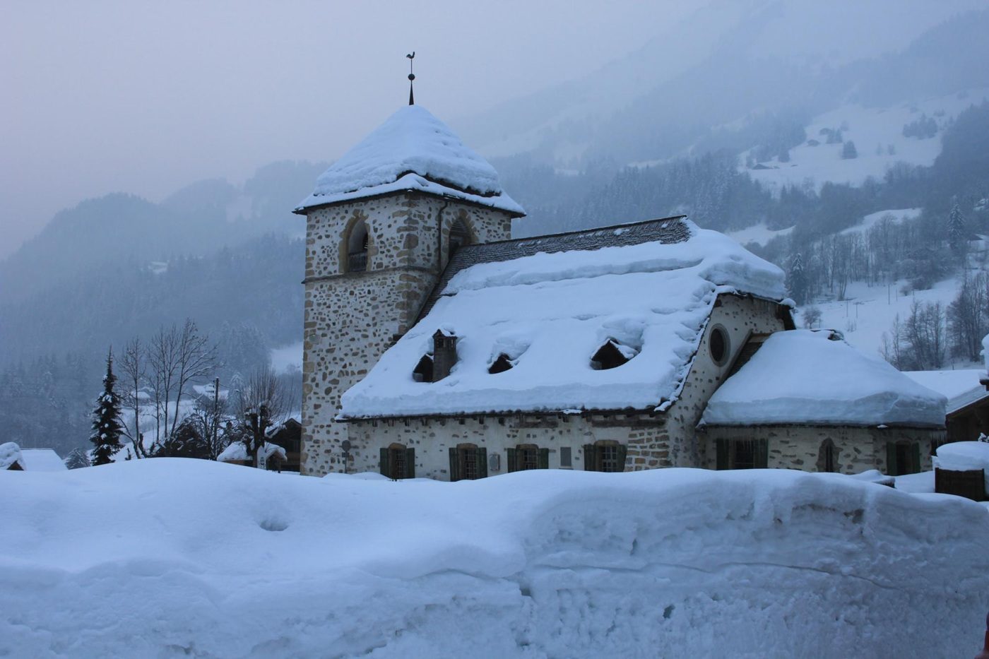 Vue extérieur du temple de Vers-l'Eglise, recouverte et entourée de neige, avec un léger brouillard sur les hauteurs