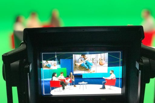 Vue d'un écran d'une caméra qui filme des participants d'une émission tv sur un plateau avec un fond vert