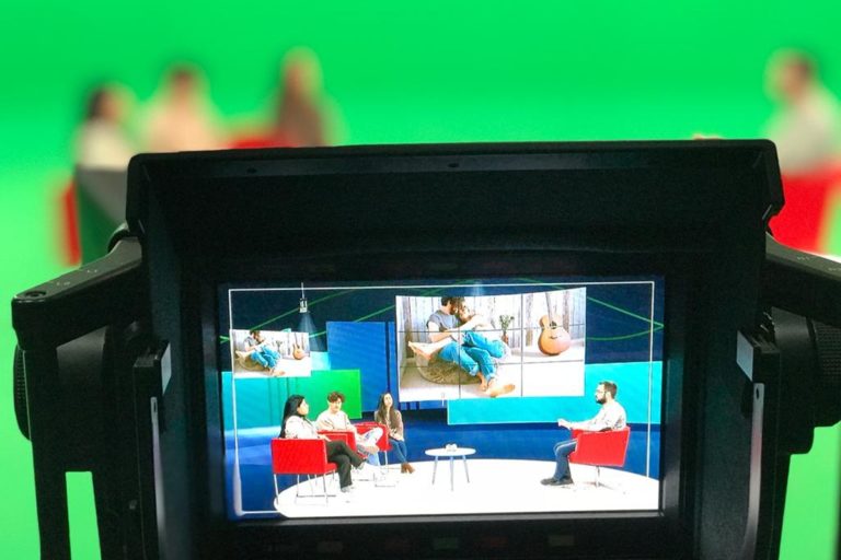 Vue d'un écran d'une caméra qui filme des participants d'une émission tv sur un plateau avec un fond vert