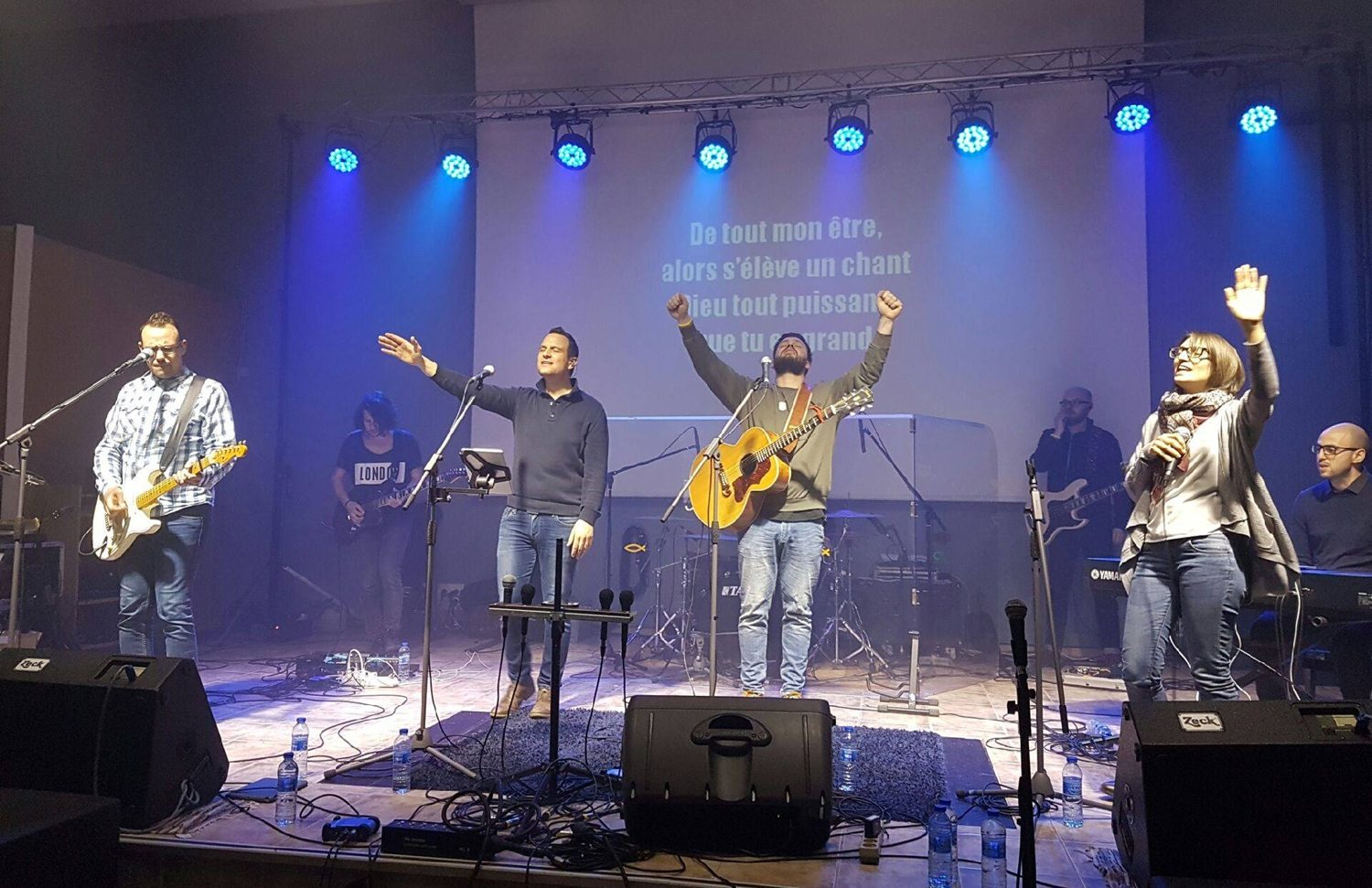 Des musiciens et chanteurs mènent un temps de louange, les bras levés vers le ciel