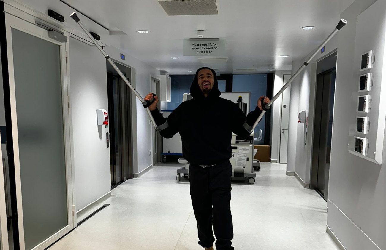 Gabriel Jesus debout dans un couloir d'un hôpital lève ses béquilles pour rassurer ses supporters