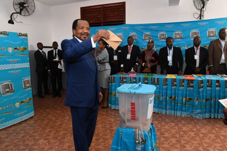 Le président Paul Biya tient une enveloppe et s'apprête à l'introduire dans l'urne de vote