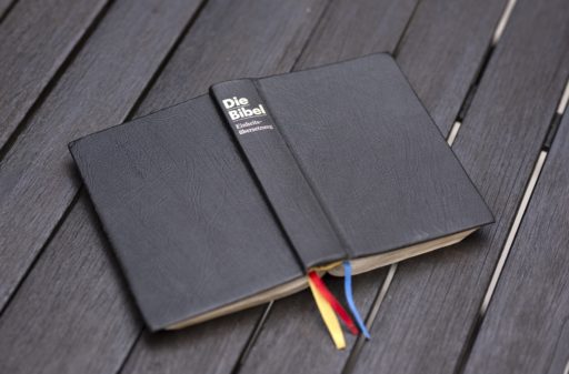 Une bible allemande posée sur un plancher en bois
