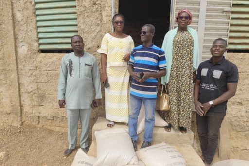 cinq personnes devant un bâtiment avec des sacs de riz à leurs pieds