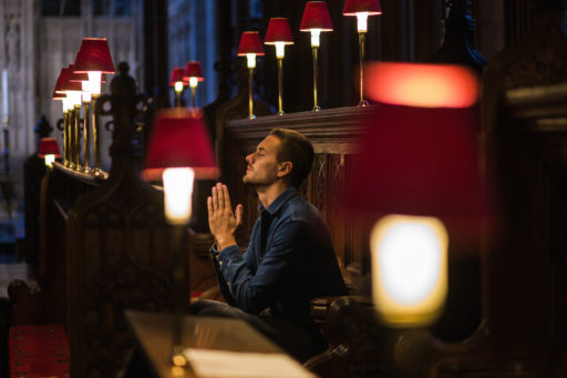 Un jeune homme agenouillé dans une église de Bristol et priant