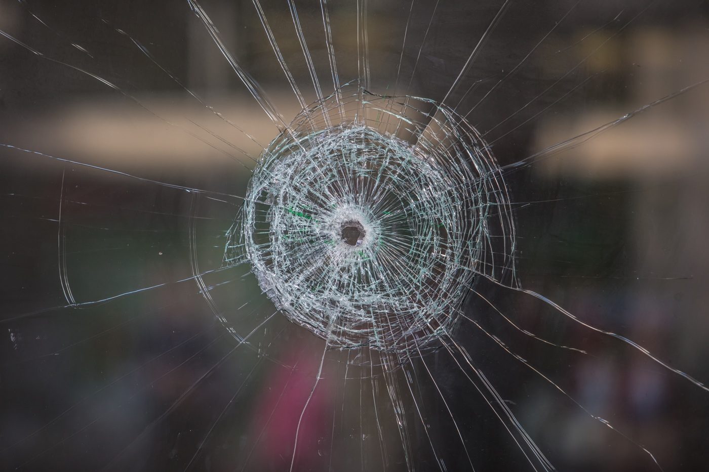un impact de balle dans une vitre fissurée