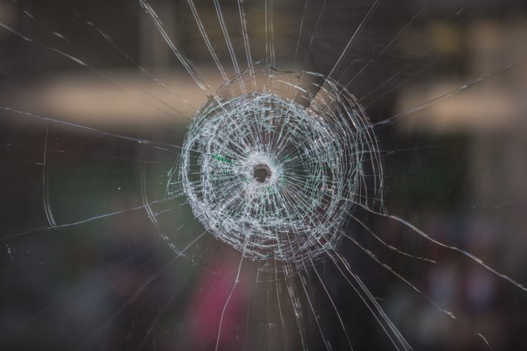 un impact de balle dans une vitre fissurée