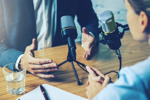Un homme parle, visage caché, face à un micro de podcast