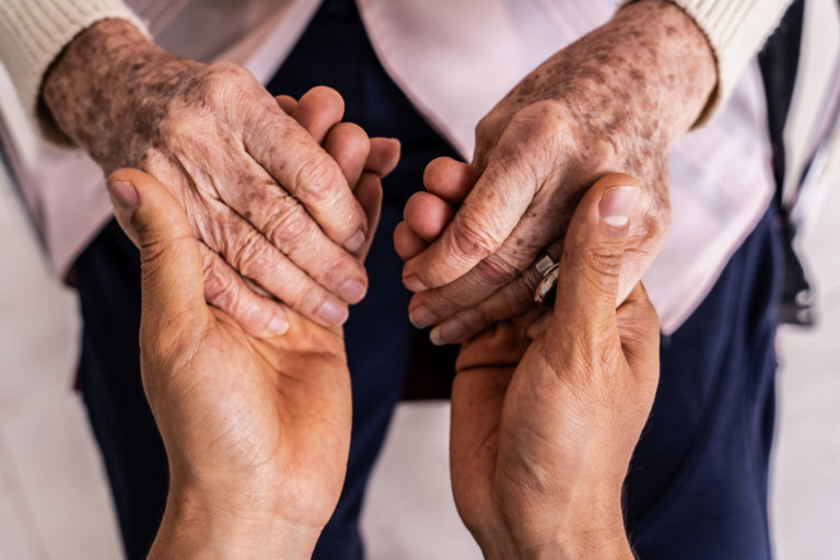 Des mains plus jeunes tiennent des mains d'une personnes âgées, vue d'en-haut